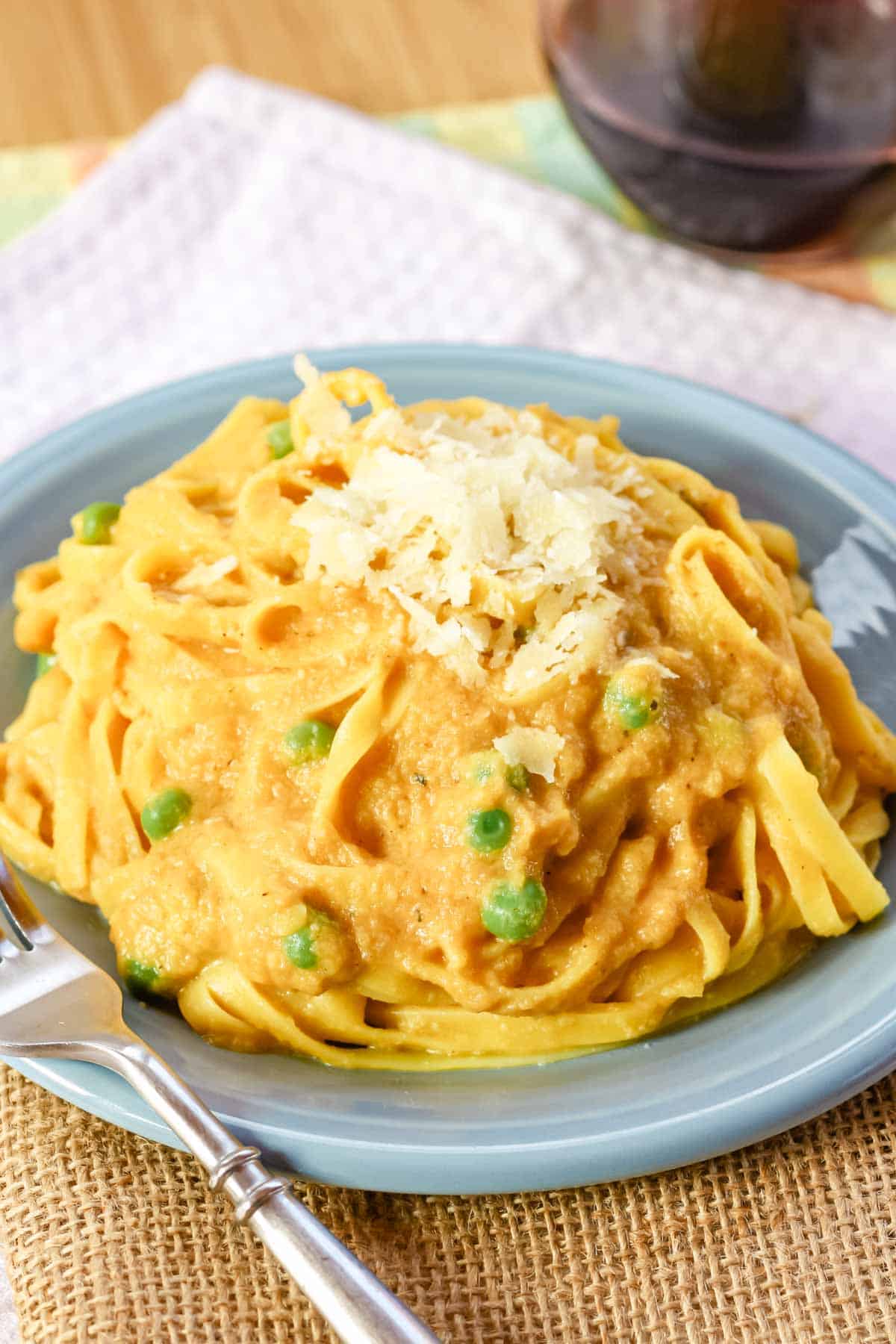 Peas peek out of a plate of pumpkin alfredo noodles.