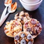 Berries top frozen oatmeal cups with bowls and spoons nearby.