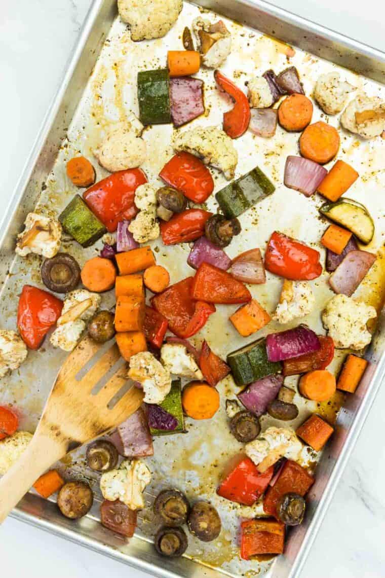 A spatula being used to toss the partially roasted veggies.