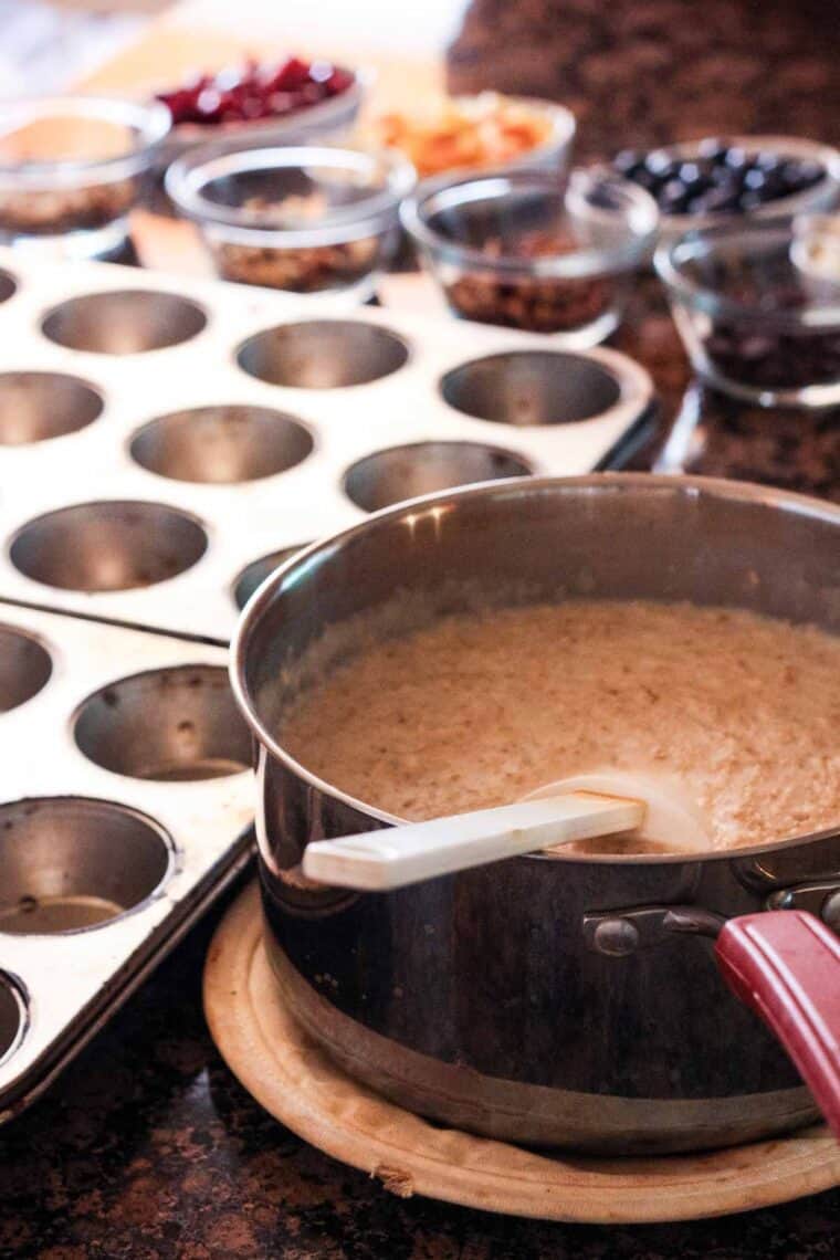 A bowl of oatmeal next to muffin tins.