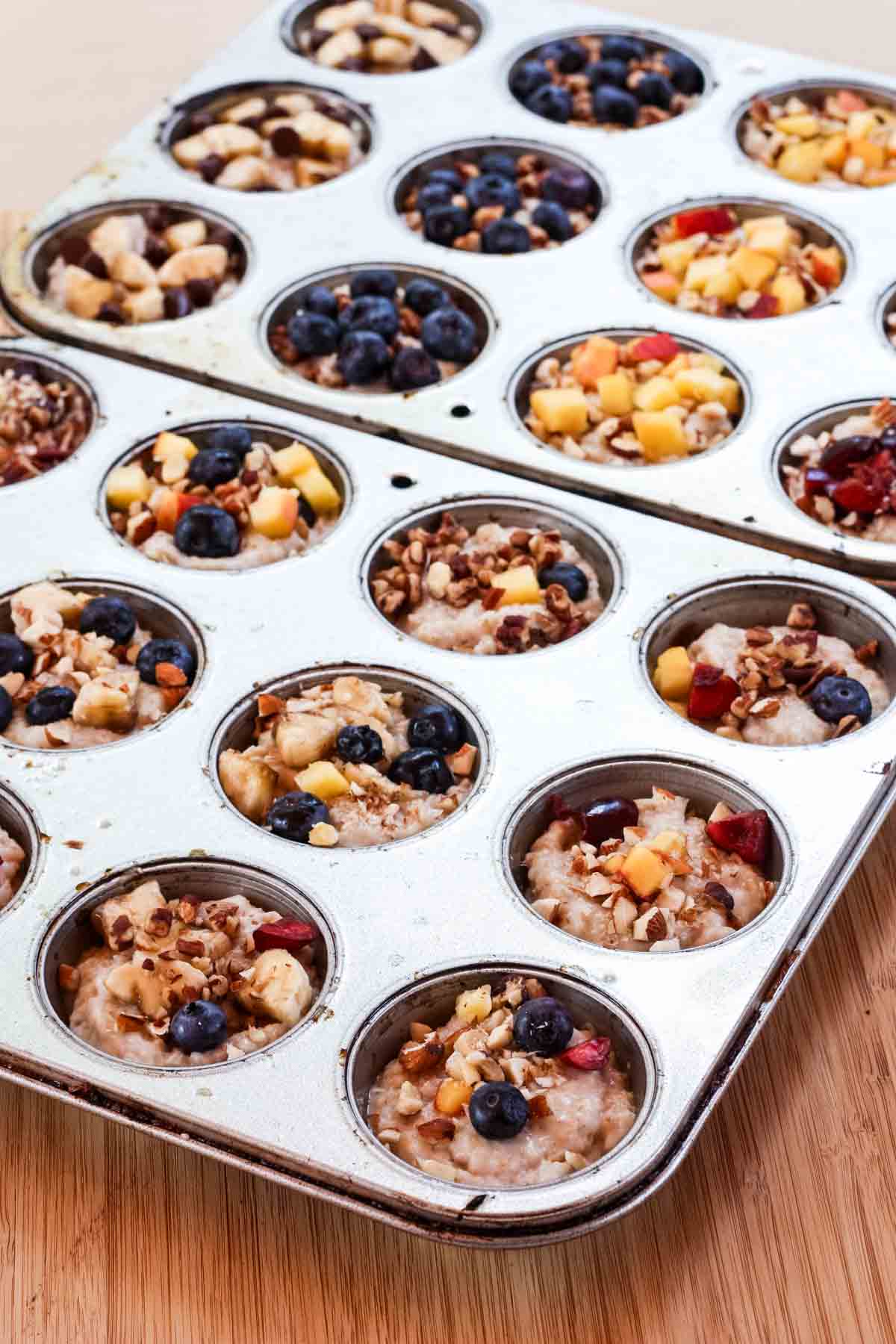 Two muffin tins filled with oatmeal topped with fruit to make frozen oatmeal cups.