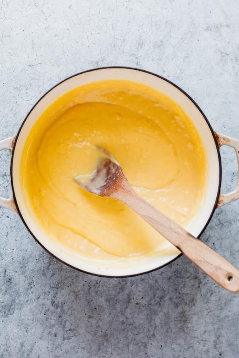 A spoon stirs the pudding in a pot.