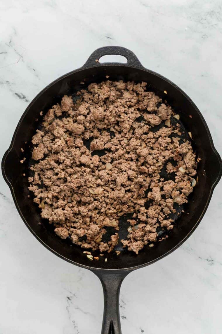 Browned ground beef in a cast iron pan.