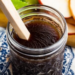 A glass jar of maple balsamic vinaigrette with a wooden spoon in it.