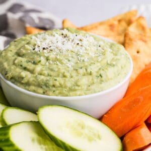 A tray with fresh vegetables and a bowl of green parmesan white bean dip.