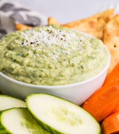 A tray with fresh vegetables and a bowl of green parmesan white bean dip.