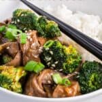 Chopsticks resting on a bowl of beef and broccoli with white rice with text overlay that says "Stir Fry Beef and Broccoli"