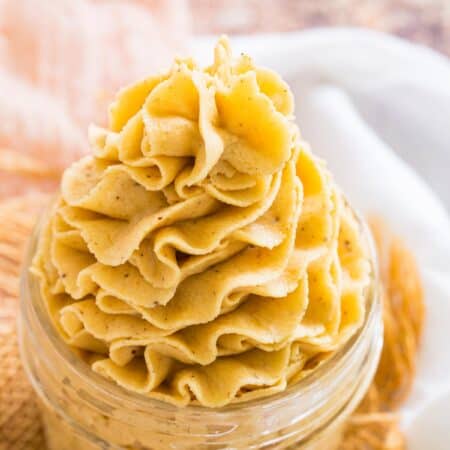 Pale orange pumpkin frosting is piped decoratively in a jar.