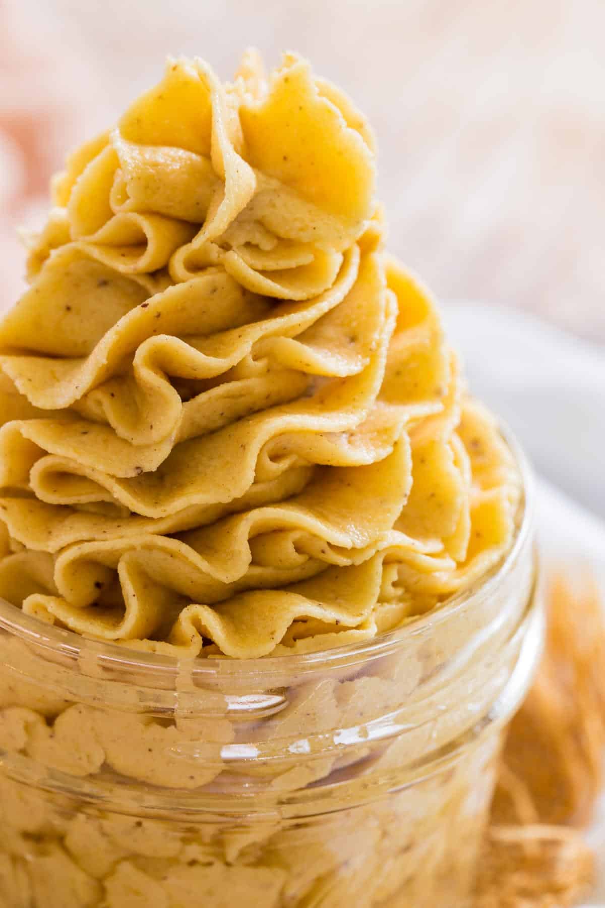 Swirls of pale orange pumpkin frosting in a glass jar.