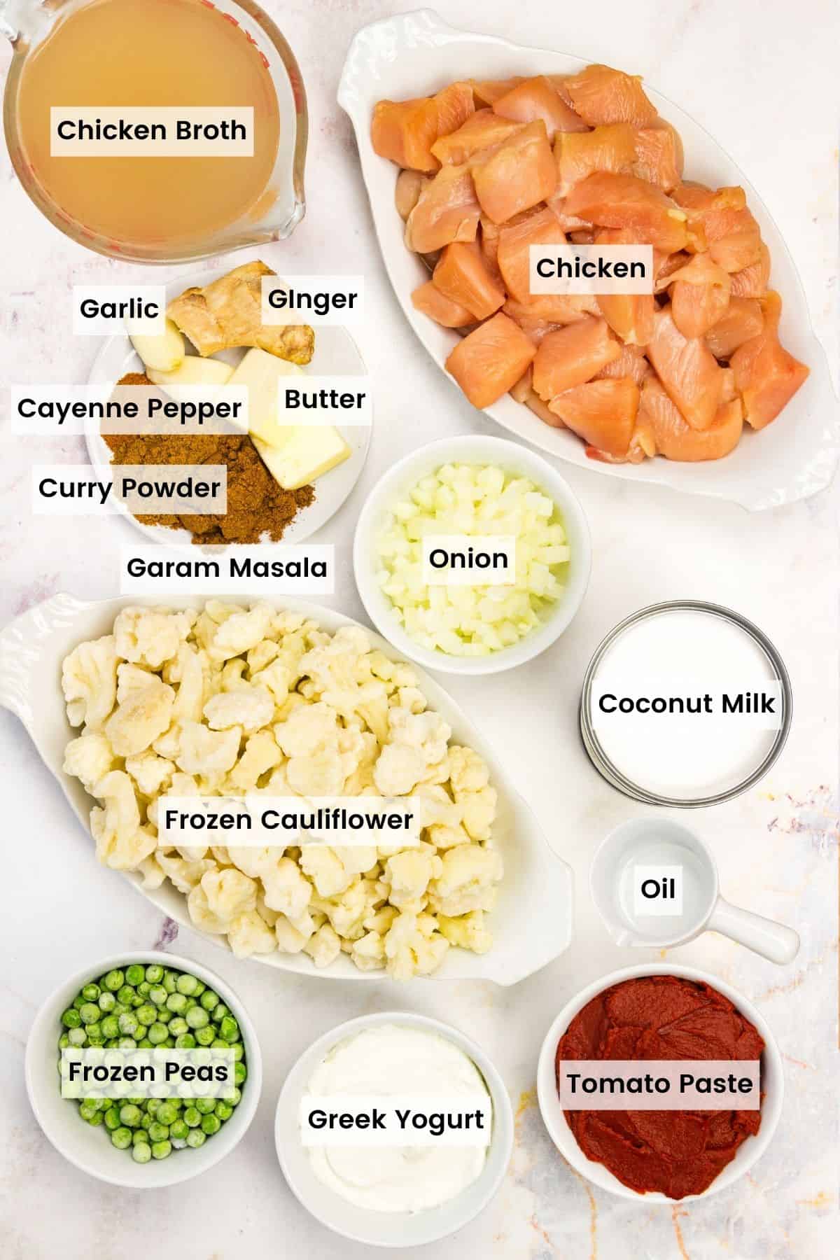 The ingredients for quick chicken curry are shown portioned out with text labels: chicken, cauliflower, peas, salt and pepper, garam masala, curry powder, cayenne pepper, oil, tomato paste, Greek yogurt, ginger, coconut milk.