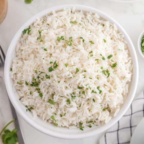 Looking down at a bowl of coconut rice garnished with cilantro.