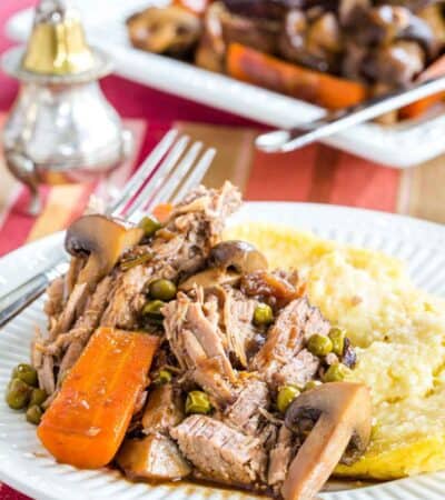 A serving of slow cooker pot roast with mashed potatoes on a plate.