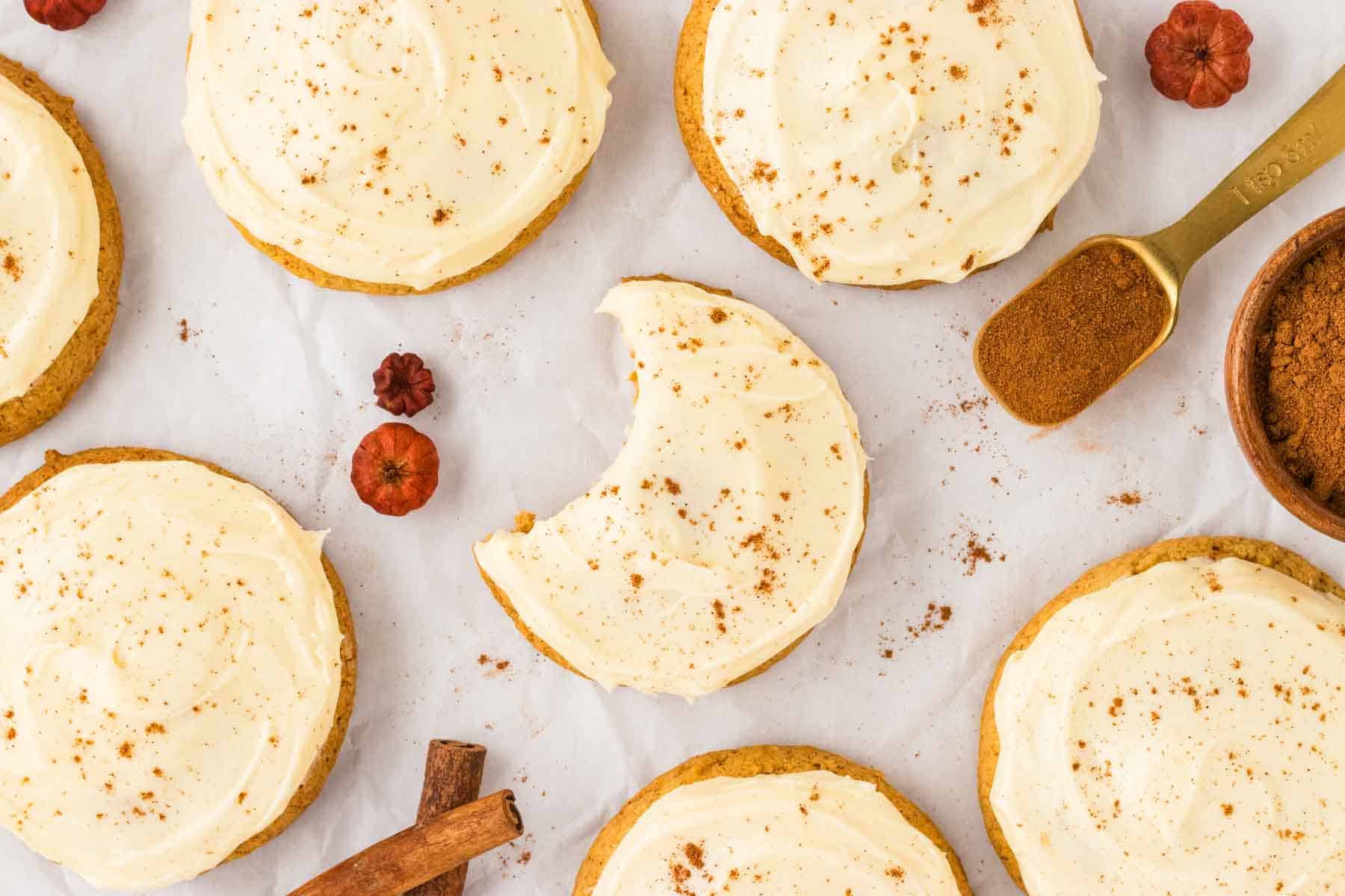 A pumpkin cookie with a bite taken out of it.