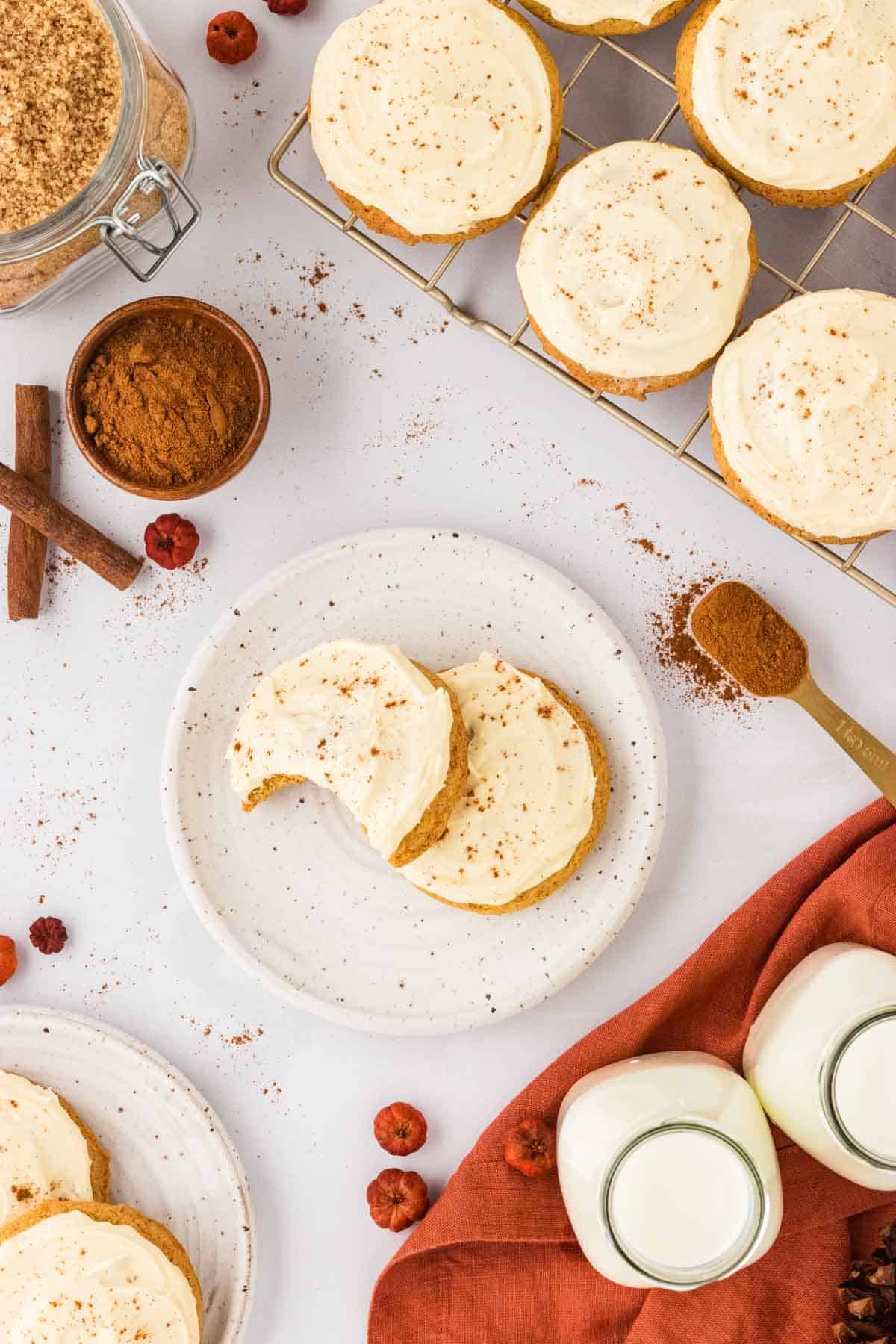 Pumpkin cookies topped with cream cheese on a plate.
