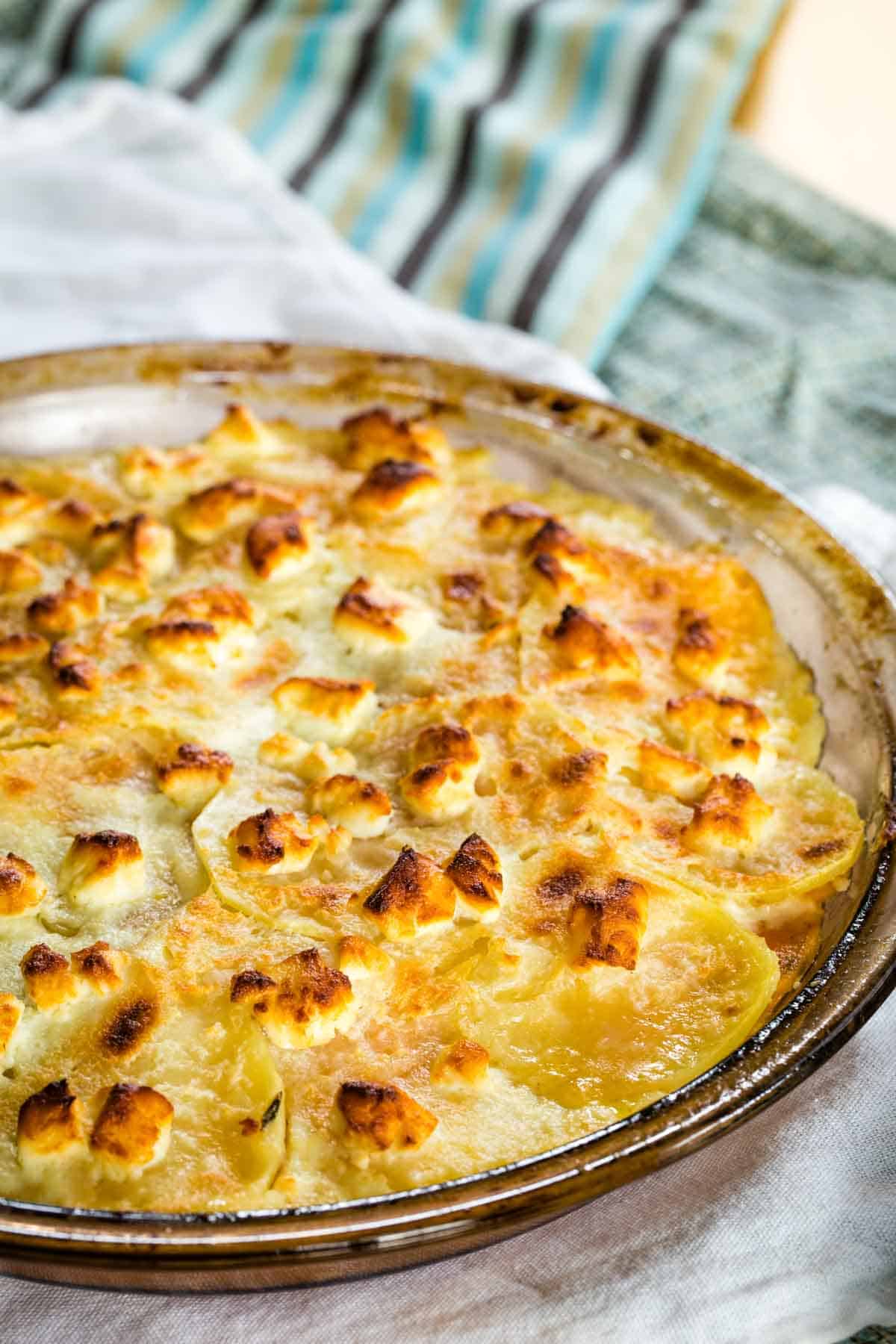 A round baking dish full of baked goat cheese sweet potato gratin.