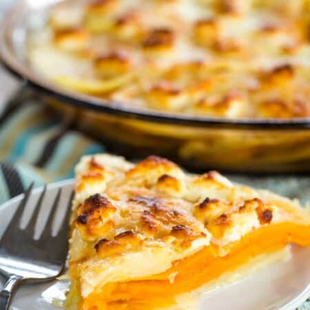 A lightly browned piece of goat cheese sweet potato gratin in front of a pan of gratin.