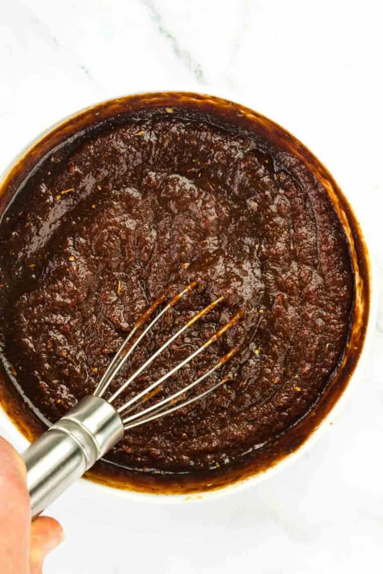 The ketchup being stirred in a bowl with a whisk.