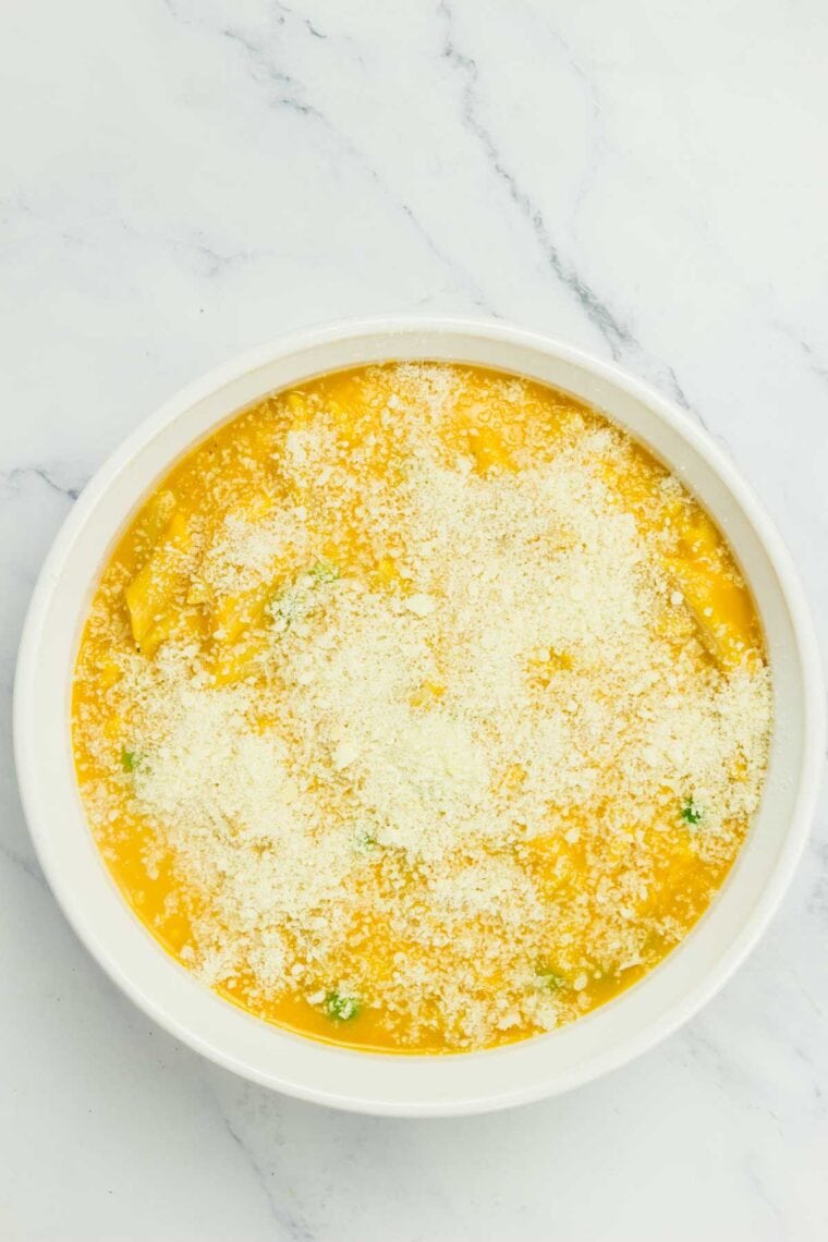 Butternut squash mac and cheese topped with parmesan in the casserole dish before baking.