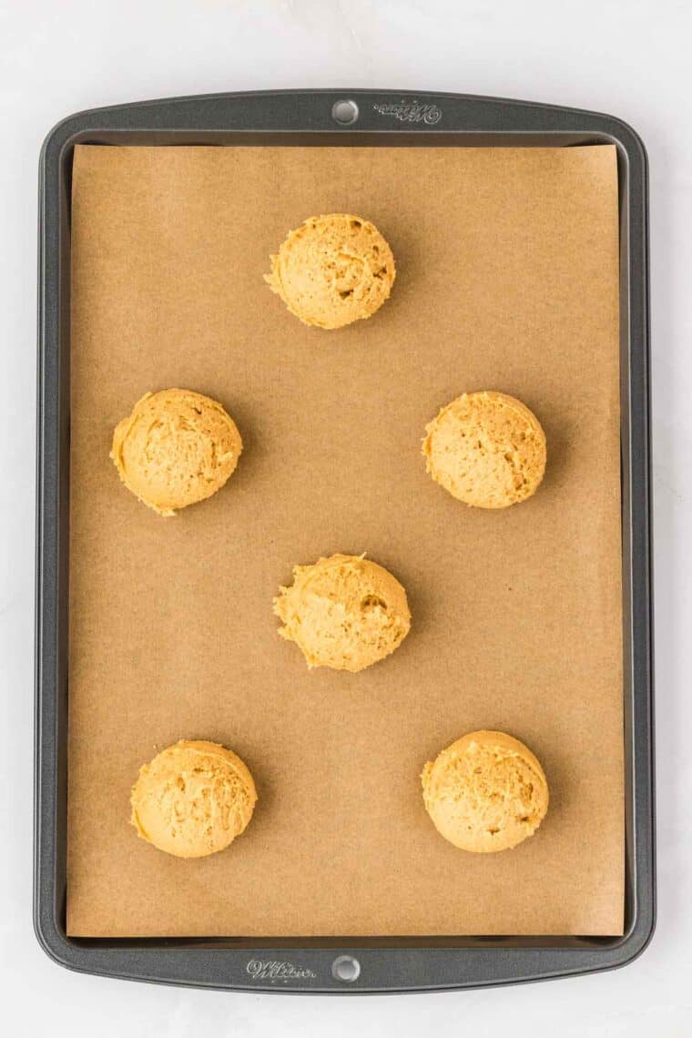 Pumpkin cookie dough balls on a baking sheet.
