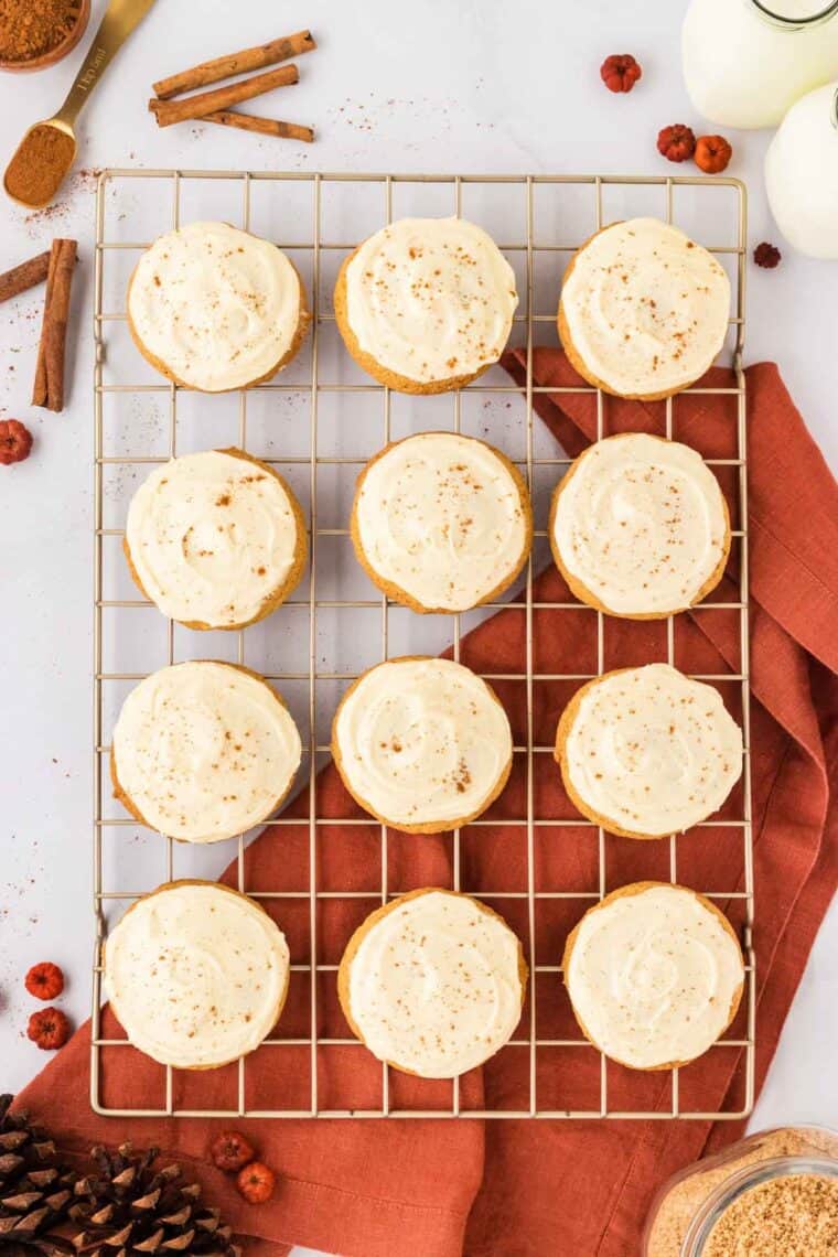Frosted pumpkin cookies on a wire rack.