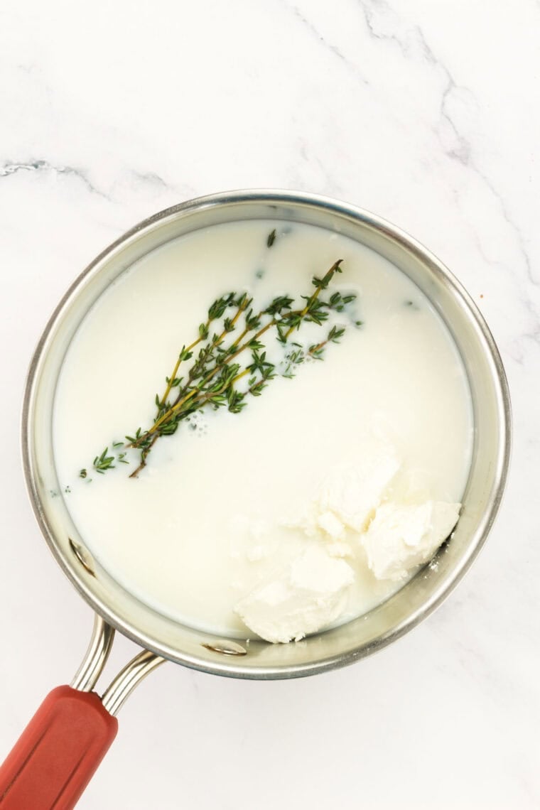 Rosemary sprigs steep in a pot of milk.