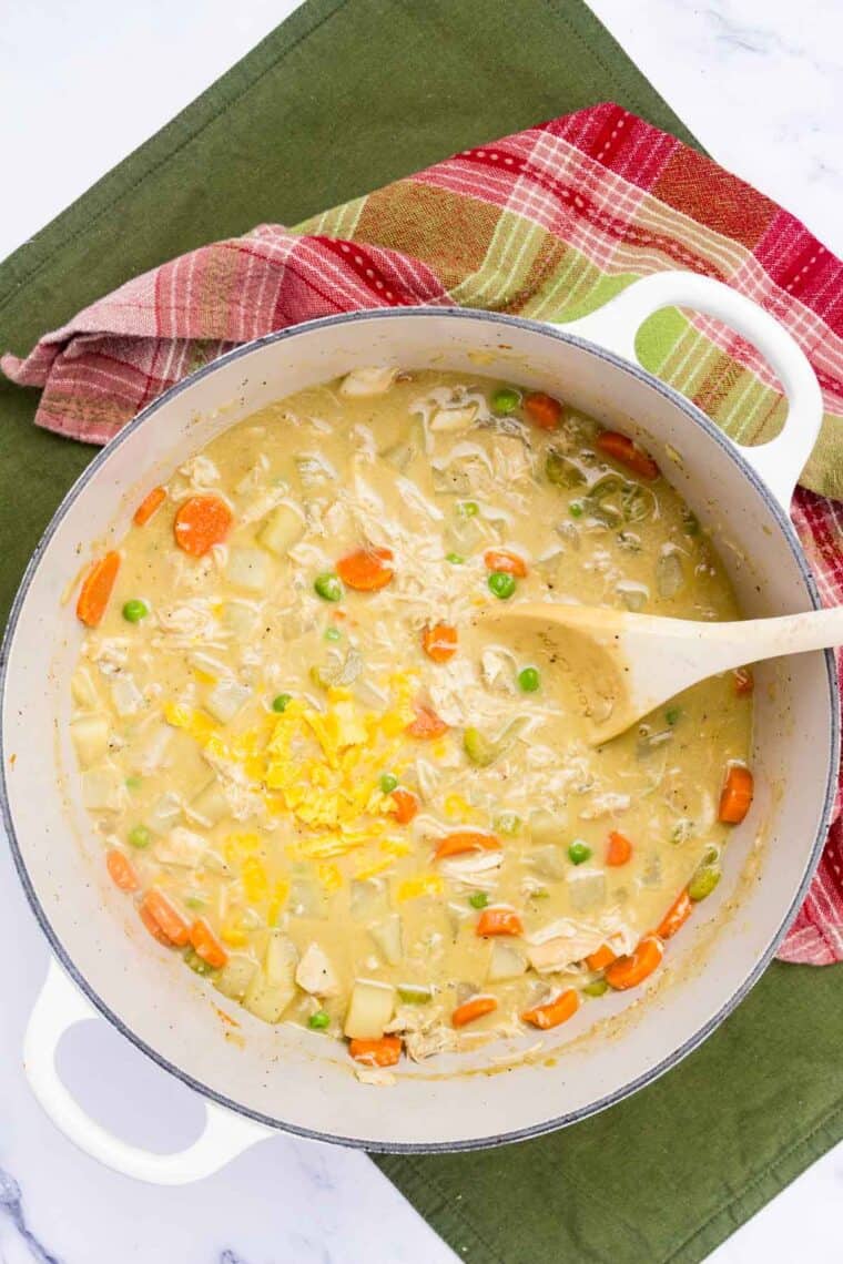 Cheese is stirred into a pot of turkey soup.