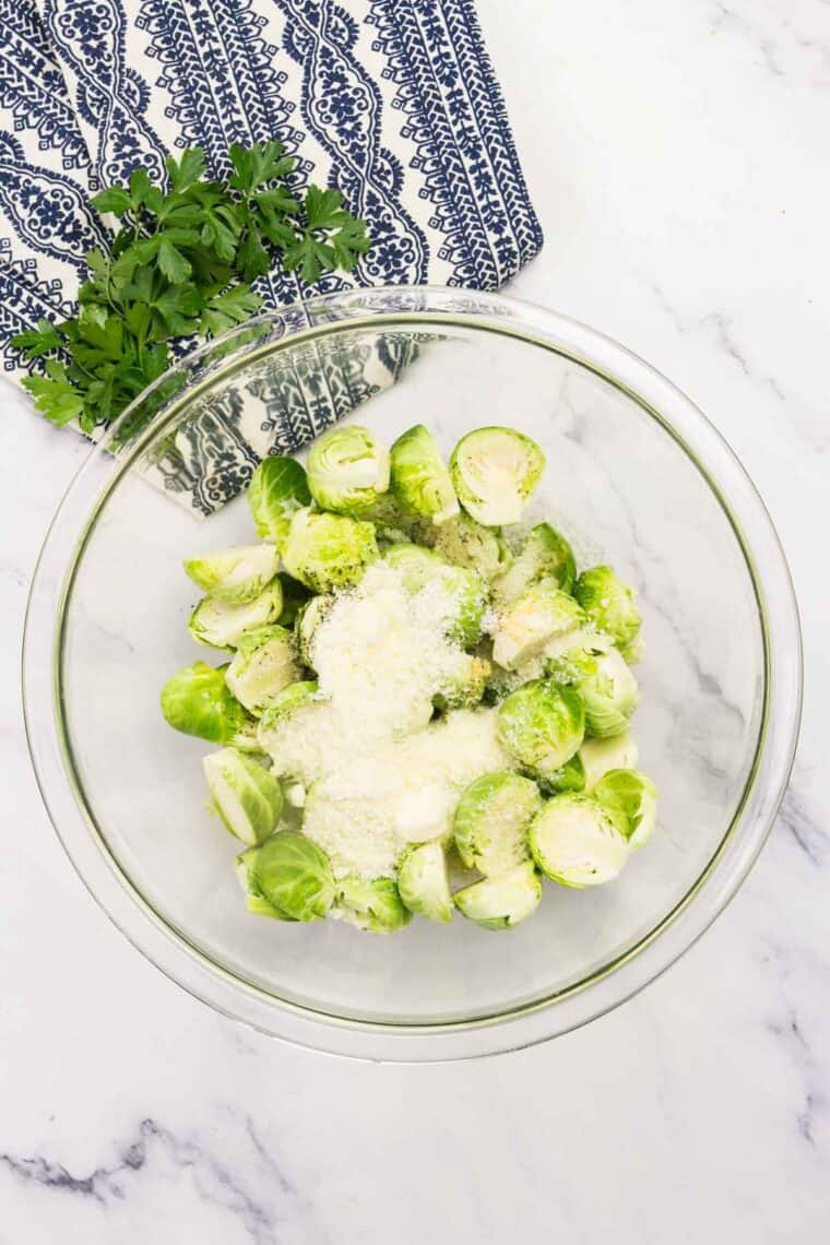 Cheese is added to bowl of Brussels sprouts.