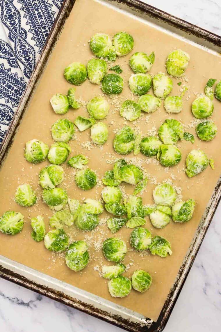 Halved Brussels sprouts on a lined baking sheet.