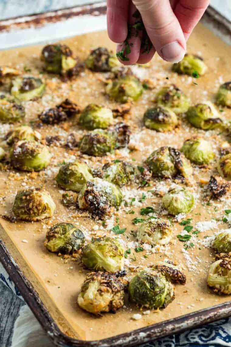 A sprinkle of parsley is added to a pan of Brussels sprouts.