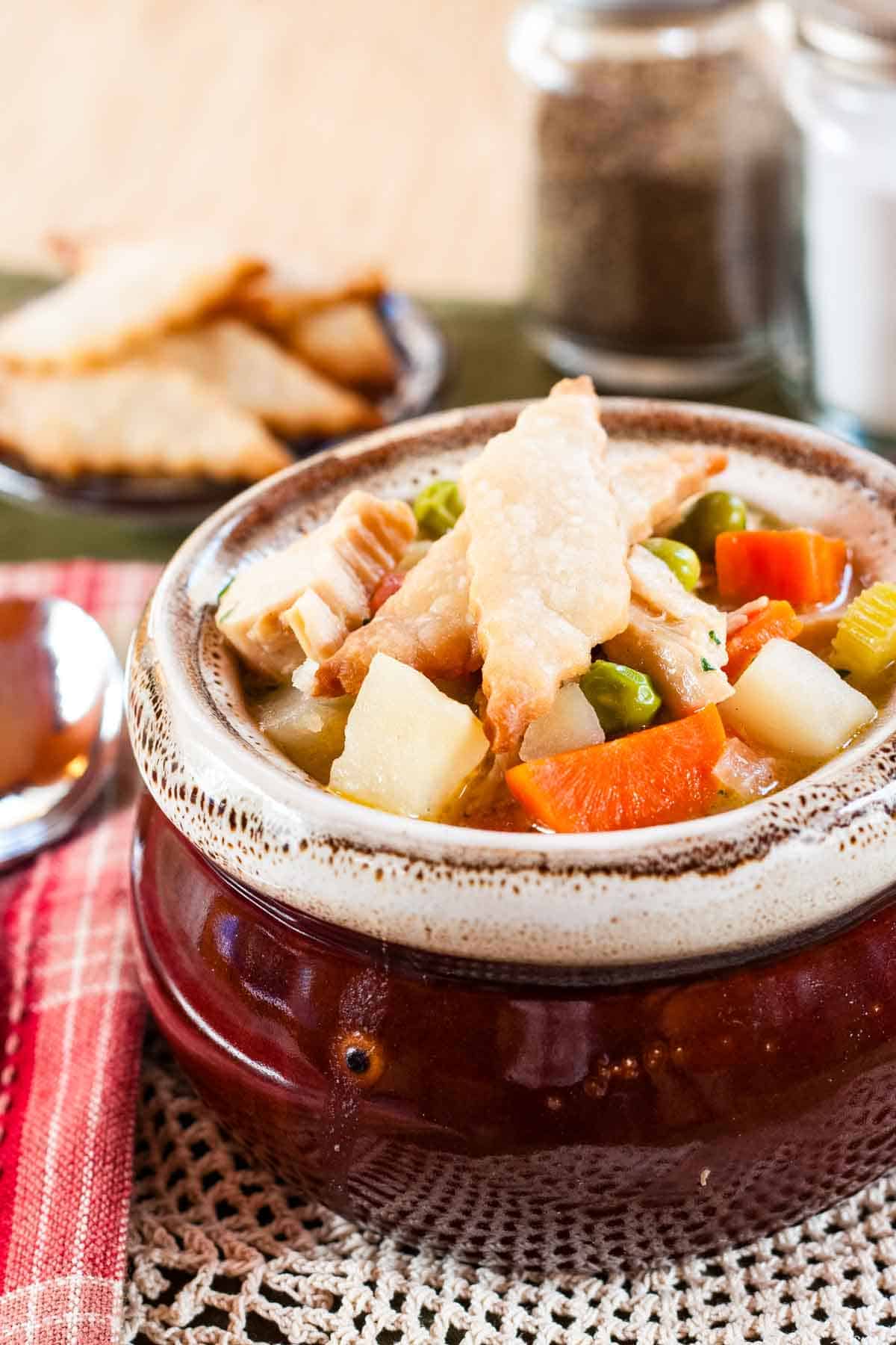 Pie crust crust crackers on the top of a bowl of turkey pot pie soup.