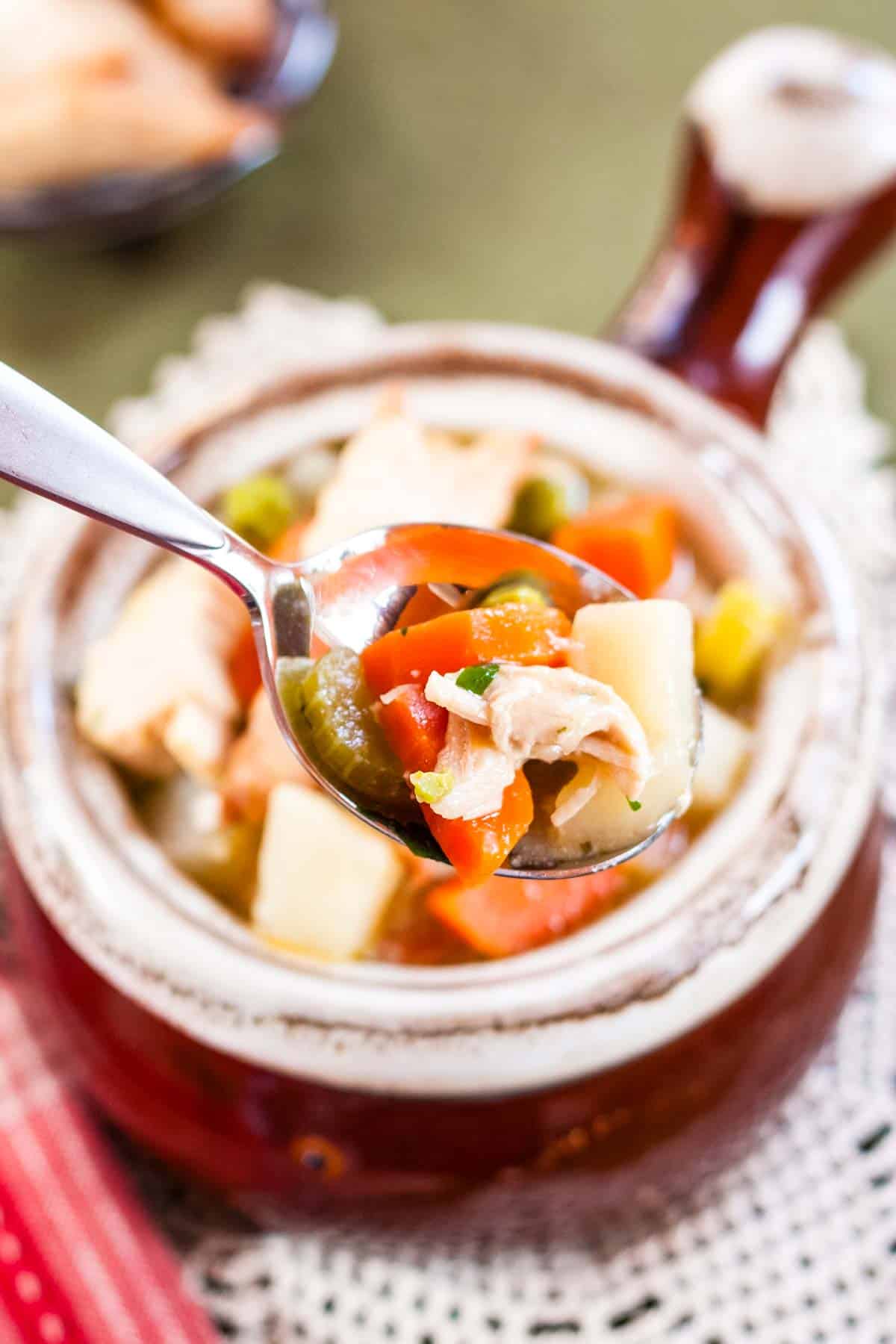 Veggies and turkey on a spoonful of soup above a bowl of soup.