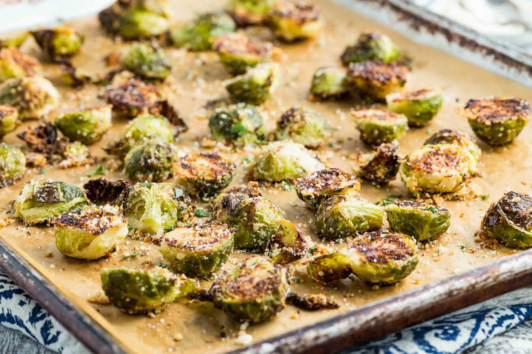 A parchment-lined baking sheet with roasted parmesan Brussels sprouts.