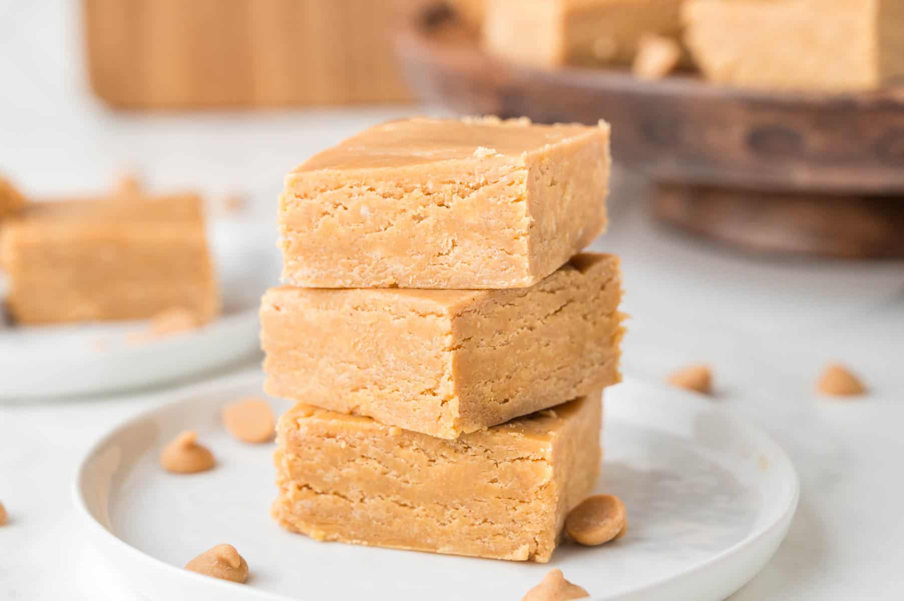 Three squares of peanut butter fudge stacked up on a white plate.