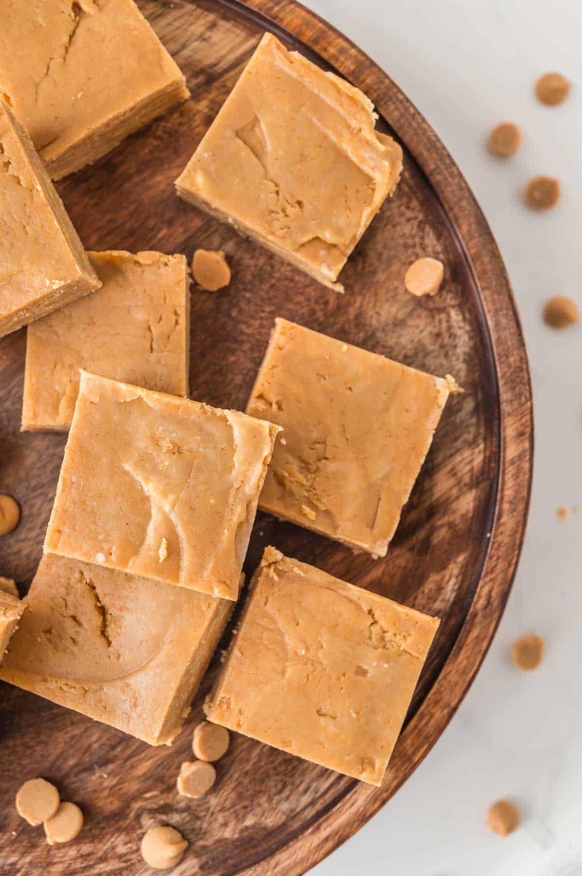 A round wooden board holds squares of peanut butter fudge.