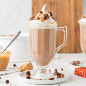 Glasses of peanut butter hot chocolate with chopped reese's around them.