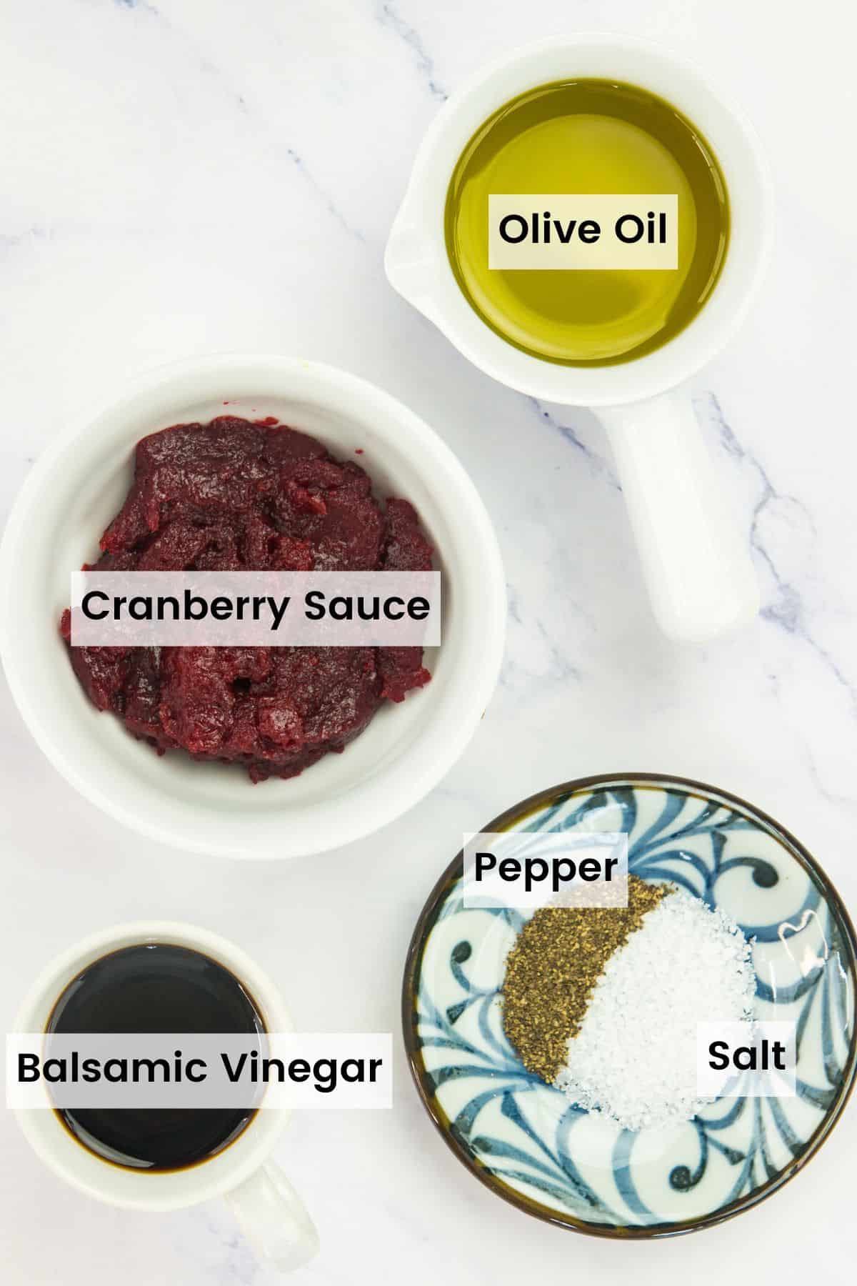 Ingredients to make cranberry balsamic dressing portioned out on a countertop with text labels.