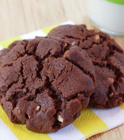 Three chocolate almond cookies on a yellow and white napkin.