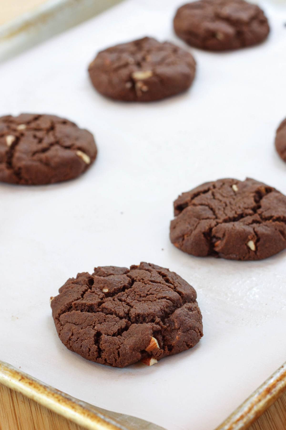 Baked chocolate almond cookies cool on a cookie sheet.