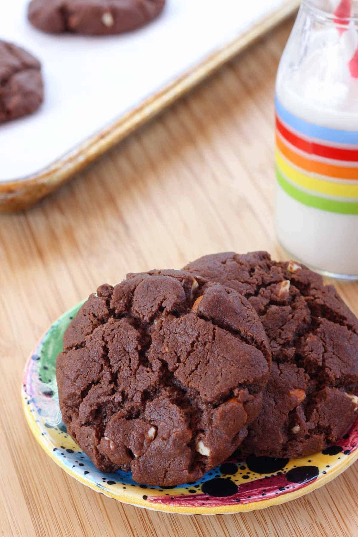 Flourless chocolate almond cookies are crisp-chewy cookies packed with almond butter and cocoa powder, brown sugar, and chopped almonds. A plate with a few flourless chocolate almond cookies.