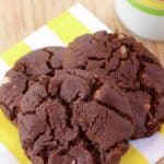 Three chocolate almond cookies on a yellow and white napkin.