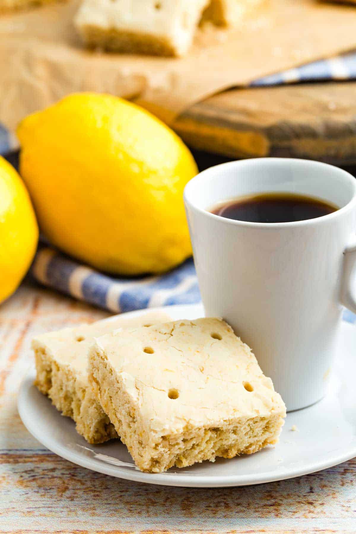 Lemon shortbread cookies on a plate with a cup of coffee or tea.