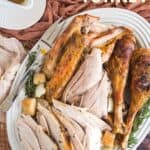 Carved turkey meat including the drumsticks on a platter with text overlay that says "Herb Roast Turkey".