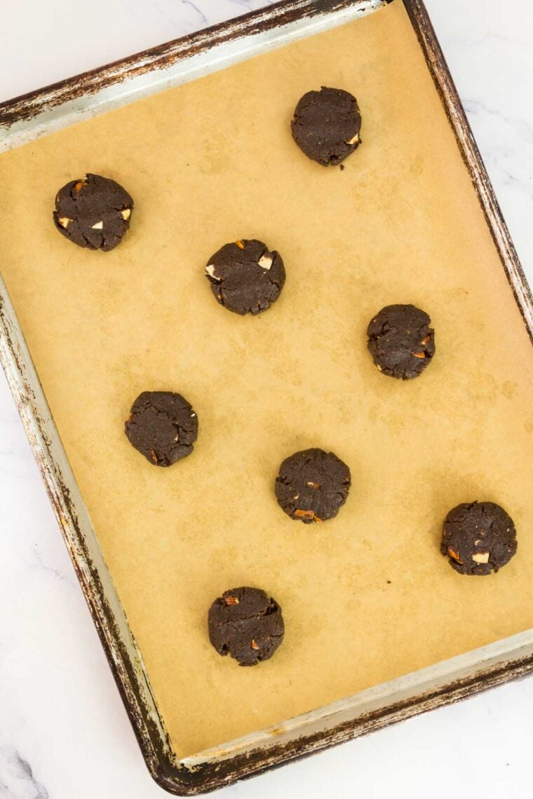 Chocolate almond cookie dough balls placed on a baking sheet.