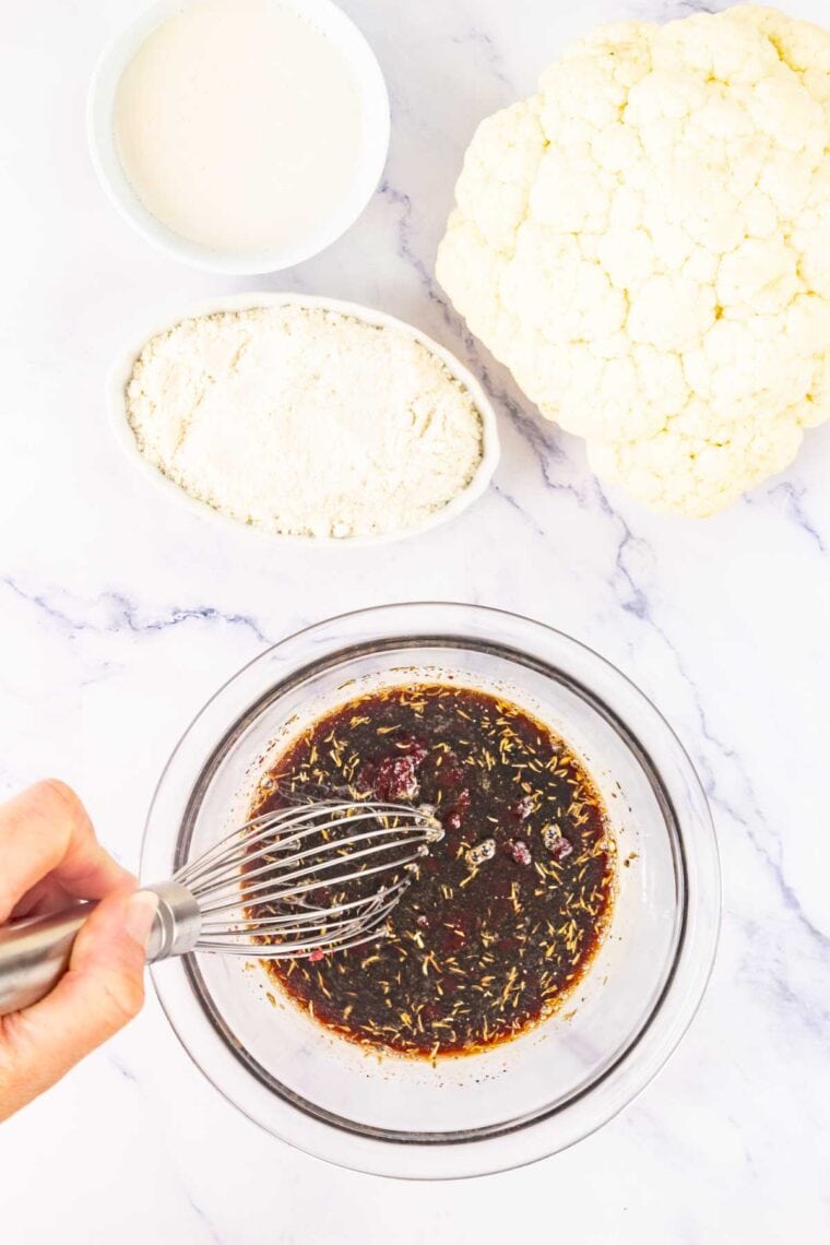 Cranberry glaze being whisked together in a bowl.
