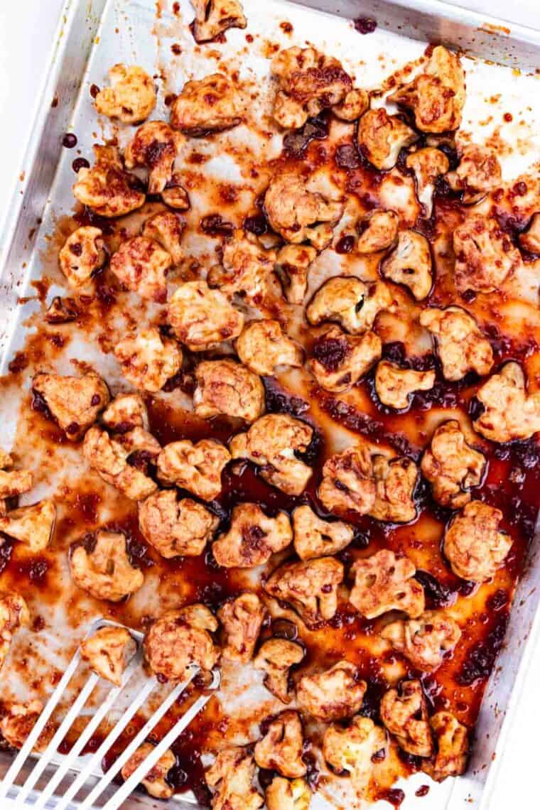 A spatula flipping glazed cauliflower.