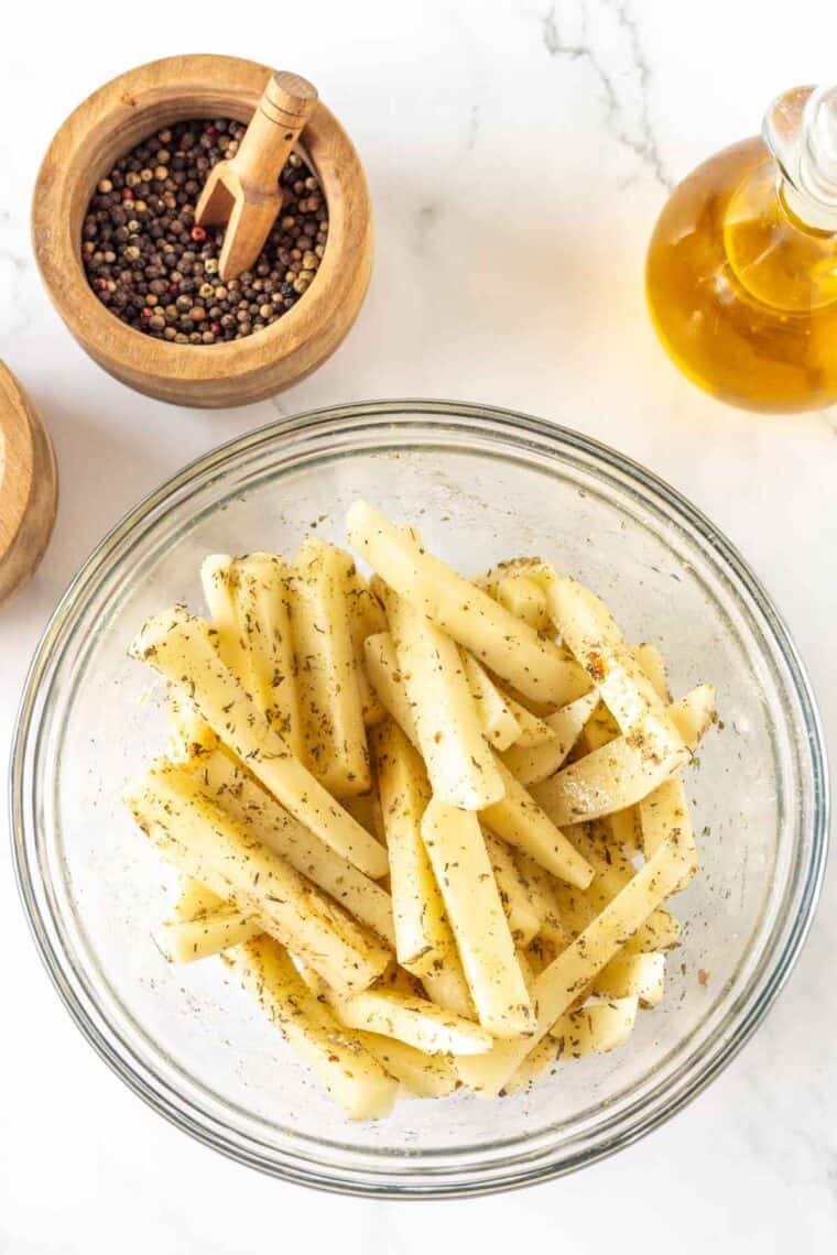 Seasonings are mixed into a bowl of potato fries.