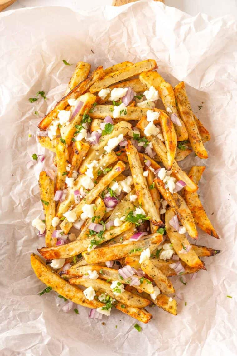 Cheese, chopped red onion, and herbs added to baked potato fries.