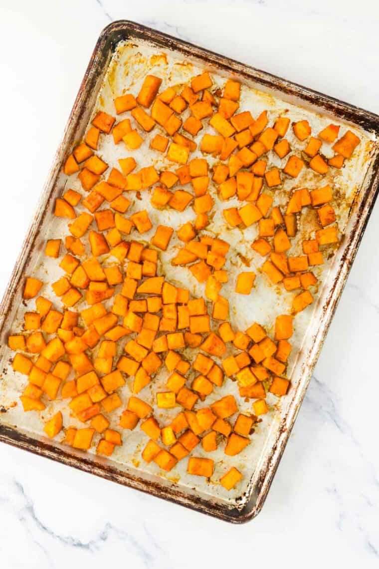 Roasted butternut squash cubes on a sheet pan.