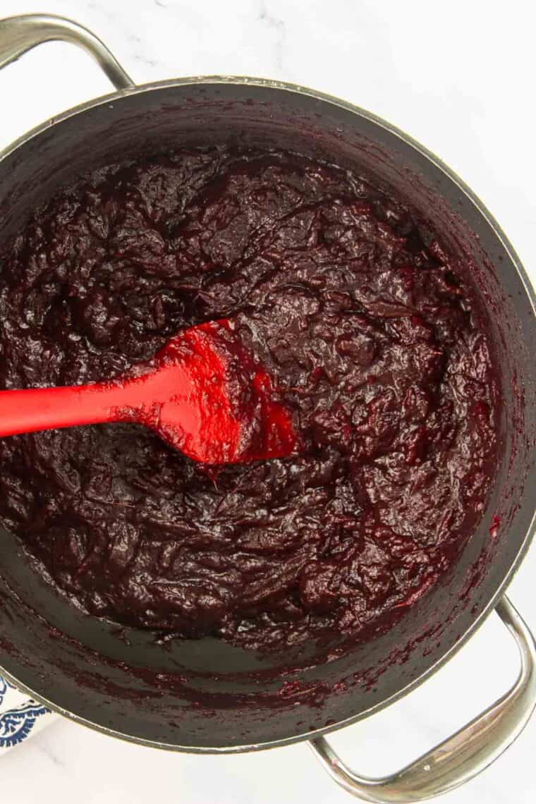 Cooked cranberry sauce in a pot with a spatula.