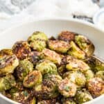 A serving bowl of roasted brussels sprouts with text overlay that says "Parmesan Roasted Brussels Sprouts".